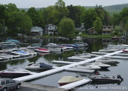 Aluminum docks in a marina with boats and residential homes in the background